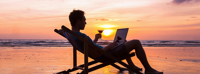 672 x 250 Man met laptop en cocktail strand zonsondergang 