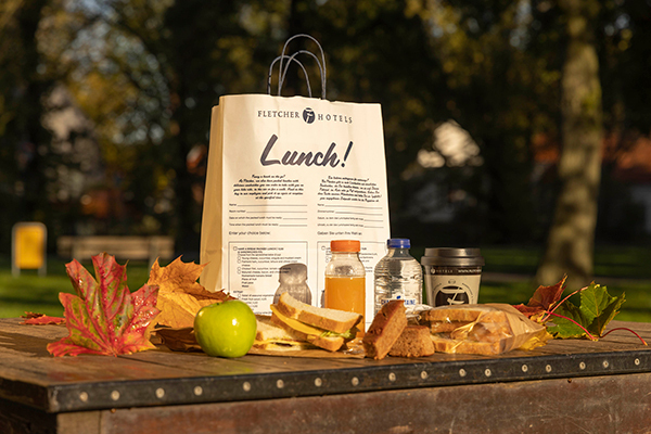 Lunchpakket met broodjes, fruit en drinken.