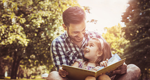 Vader en dochten lezen een boek midden in de natuur