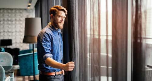 Man kijkend uit het raam van een hotel