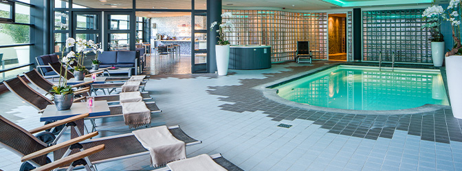 Binnenzwembad en loungestoelen van BLUE Wellness Trivium